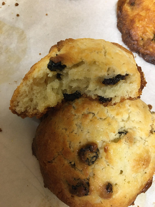 Gluten free drop scone baked to golden brown colour, one piece broken showing airy centre on a white plate