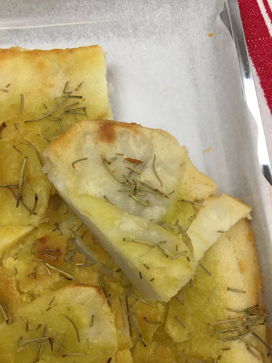 Gluten Free Crispy Potato Bake topped with rosemary on parchment lined sheet.