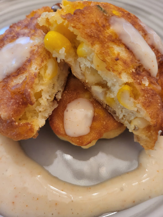 Gluten Free Corn Fritter sliced in half on a beige plate showing the corn kernels and light fluffy cooked fritter batter.