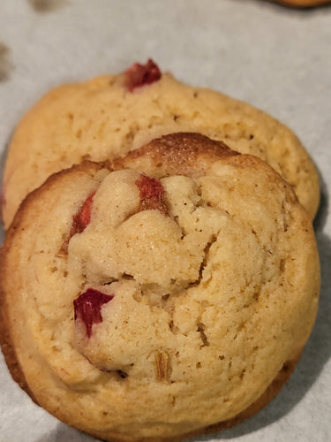 Two golden baked cookies with rhubarb placed on parchment.
