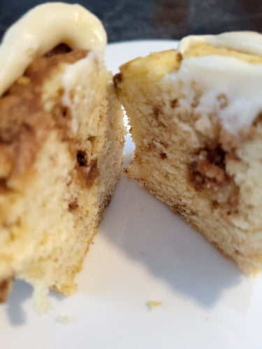 Cinnamon infused muffin topped with cream cheese icing on a white plate.