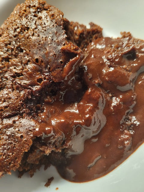 Gluten free chocolate pudding cake, with pudding mixture flowing out on a white plate.