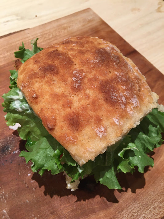 Gluten free ciabatta bun sandwich on a wooden cutting board.