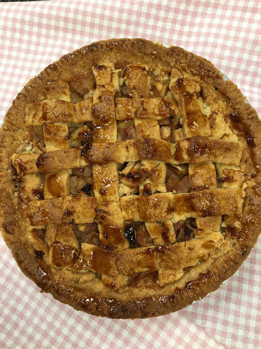Golden baked gluten free applie pie with lattice topping on a pink and white checked table cloth.