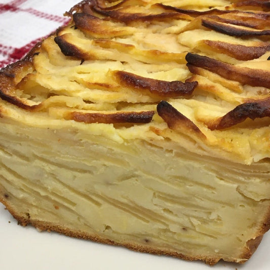 A gluten free apple layer cake on a white plate with red and white checked cloth in background.  Cake is baked with QUeen Milling gluten free flour.
