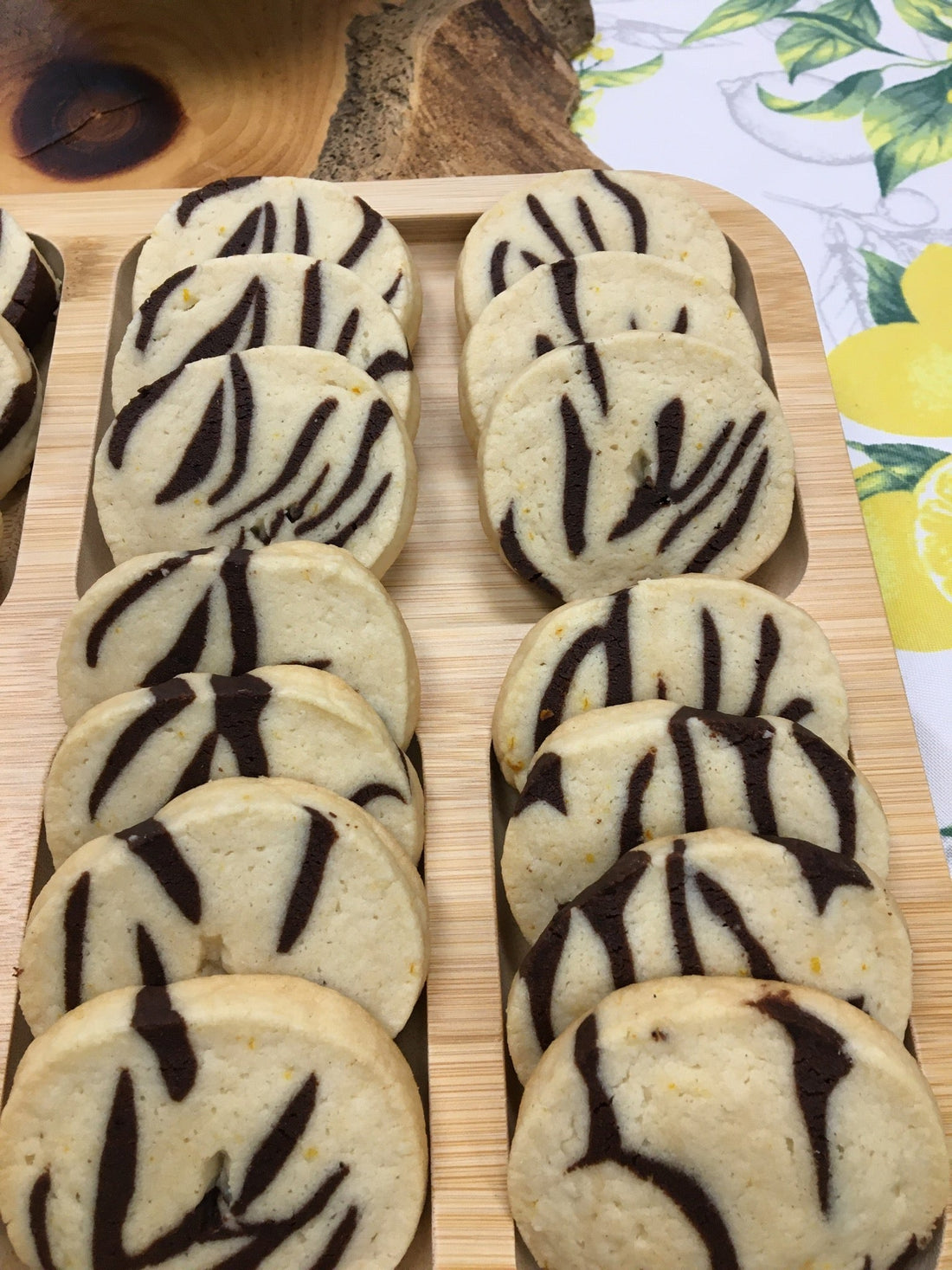 Two rows of variegated icebox cookies on a wooden tray with colourful background