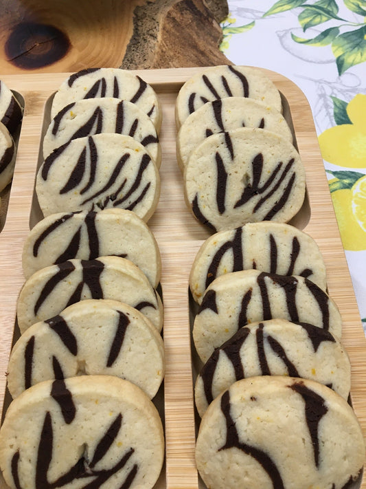 Two rows of variegated icebox cookies on a wooden tray with colourful background