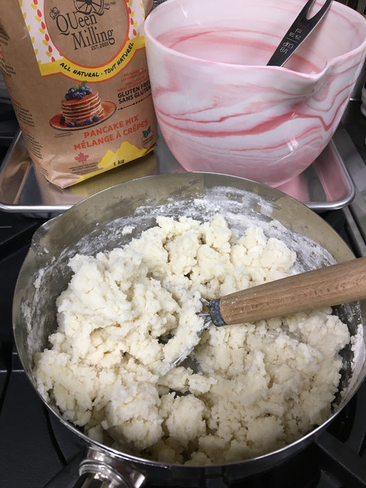 a bowl with gluten free dough, a bag of QUeen Milling Superfine Pancake Mix in the background with a pink and white bowl beside it.