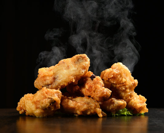 Gluten free chicken wings with steam rising on a black table top and black background.