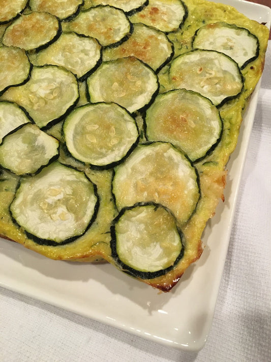 White plate with zucchini topped gluten free base.  Baked golden